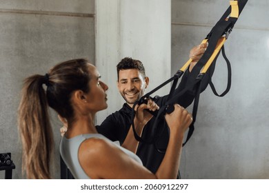 Smiling Male Coach Helps Woman With Suspension Strap Workout At Gym Hiit Class.