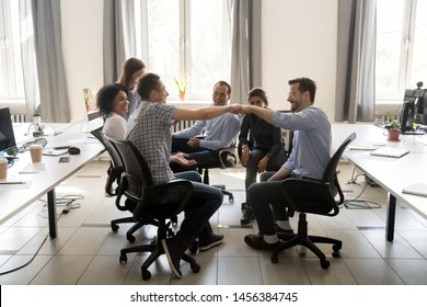 Smiling male colleagues involved in group teambuilding activity join hands motivated for shared goal, happy coworkers give fists bump greeting at meeting or congratulating with achieved success - Powered by Shutterstock