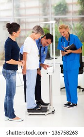 Smiling Male Doctor Measuring Patient's Height And Weight On Scale