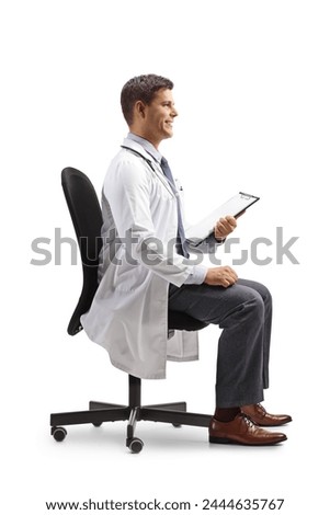 Smiling male doctor sitting in an office chair and holding a clipboard isolated on white background