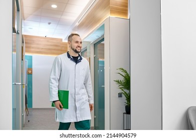 Smiling Male Doctor Walking Through Hospital Hallway