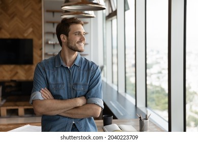 Smiling male employee stand at workplace look in window distance thinking pondering of future caress opportunities perspectives. Happy man imagine visualize success. Business vision concept. - Shutterstock ID 2040223709