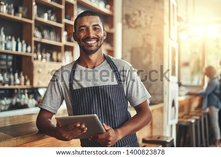 Smiling male entrepreneur in his coffee shop holding digital tab