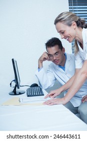 Smiling male and female dentists using computer