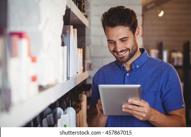 Smiling male hairdresser using digital tablet at a salon - Powered by Shutterstock