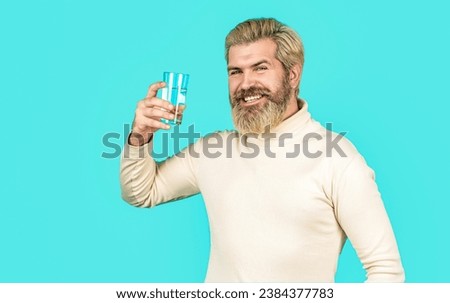 Smiling male holding transparent glass in her hand of water. Man drinking from a glass of water. Health care concept photo, lifestyle. Happy beard man drinking water.