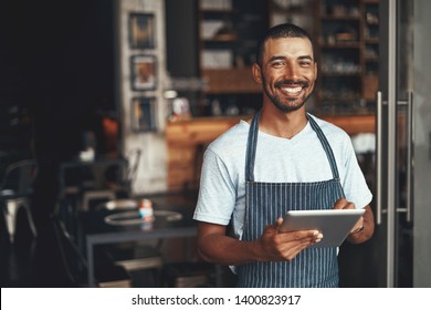 Smiling male owner standing at the doorway of his cafe - Powered by Shutterstock