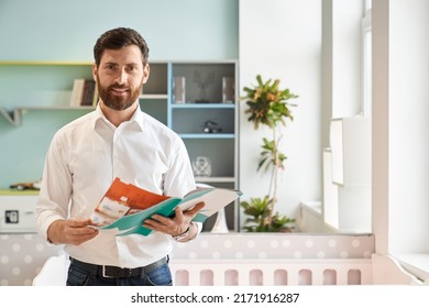 Smiling male sales manager holding catalogue of various furniture, while standing in light showroom. Portrait of bearded customer flipping brochure, while choosing goods. Concept of interior design. - Shutterstock ID 2171916287