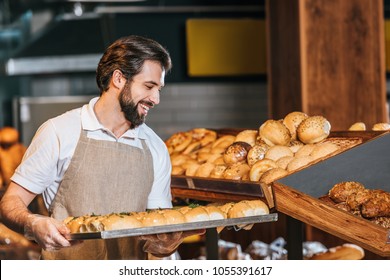 Smiling Male Shop Assistant Arranging Fresh Pastry In Supermarket