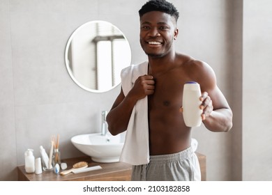 Smiling  Male Showing Shower Gel Bottle Standing In Bathroom At Home, Wrapped In Towel. Man Advertising Shampoo Or Body Lotion. Selective Focus On Man. Cosmetics For Selfcare - Powered by Shutterstock