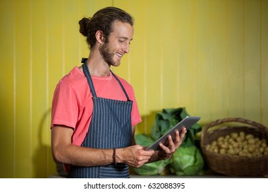 Smiling male staff using digital tablet in organic section of supermarket - Powered by Shutterstock