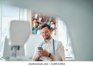 Smiling Male Tailor Messaging On Smartphone At Workplace