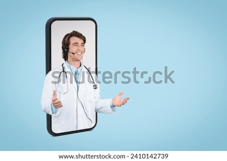 Smiling male telemedicine doctor displayed on smartphone screen with headset, engaging with viewers through friendly gesture, on blue background, free space