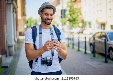 Smiling Male Tourist Uses A Smartphone During A Summer City Break