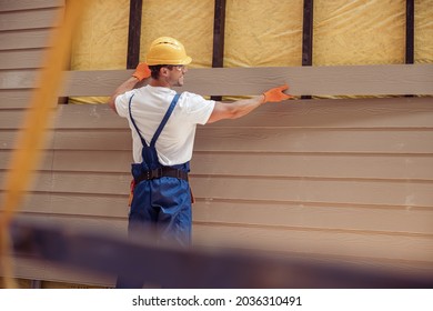 Smiling male worker building cabin at construction site