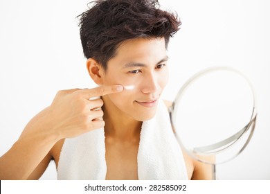 Smiling Man Applying Cream Lotion On Face