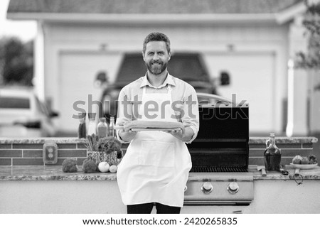smiling man barbecuing trout fillet. man barbecuing trout fillet outdoor. man barbecuing trout