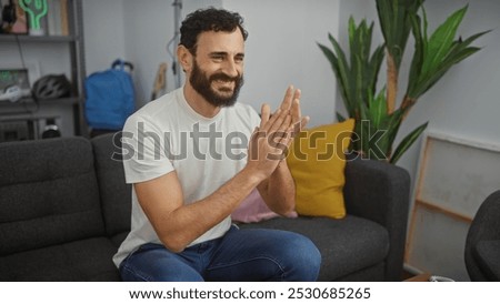 Smiling man with beard clapping hands in modern living room
