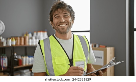 Smiling man with beard wearing volunteer vest holding clipboard in warehouse - Powered by Shutterstock