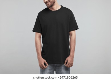 Smiling man in black t-shirt on grey background, closeup