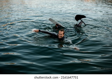 Smiling Man In A Black Wetsuit With A Foil Wakeboard Swims In The Water. Summertime Watersports Activity