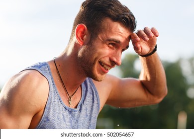 Smiling man in blue t-shirt wiping sweat on nature - Powered by Shutterstock