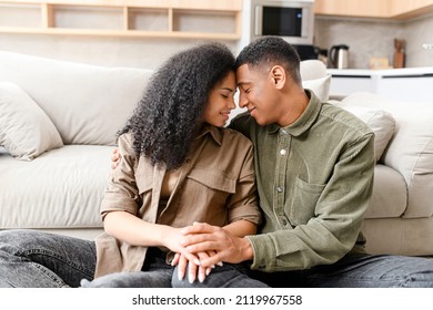 Smiling Man Bonding To His Charming Multiracial Woman. Two People Sitting At The Carpet With Closed Eyes. Young Couple Happily Spending Time At Home