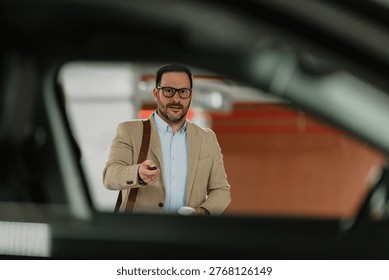 Smiling man with briefcase using car remote control while walking in an underground parking garage, representing modern lifestyle and technology