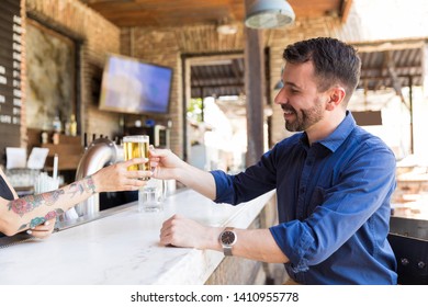 Smiling Man Buying Beer From Bartender At Counter In Bar