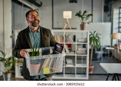 Smiling Man Carrying Plastic Box With Office Supplies While Entering The Office