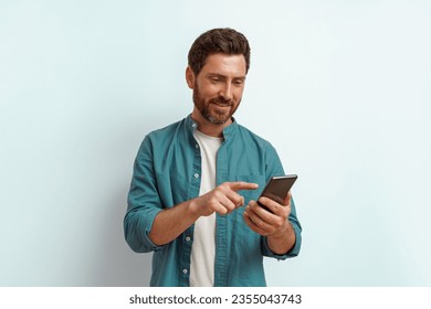 Smiling man in casual clothes use his mobile phone while standing on white background - Powered by Shutterstock