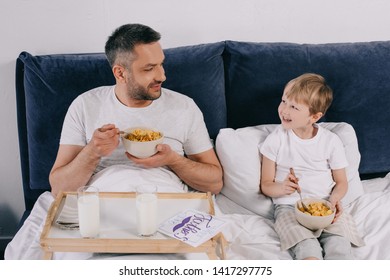 Smiling Man With Cheerful Son Having Breakfast In Bed On Fathers Day Together