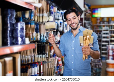 Smiling Man Choosing Tools For Home Renovation In Paint Store