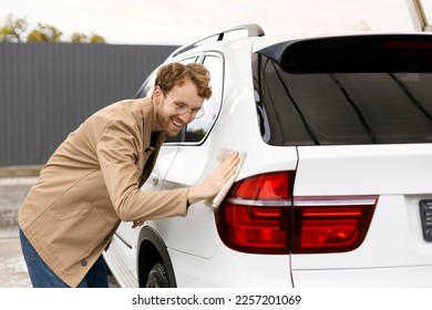 Smiling man clearing car using micro fiber cloth. Car service concept 