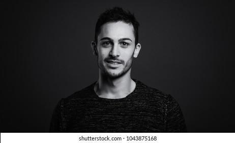 Smiling Man Close Up Portrait Against Dark Grey Background. Black And White Image.