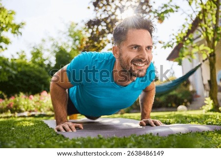 Smiling man doing pushups in the backyard garden