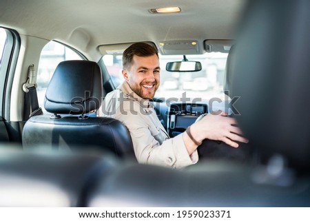 Smiling man driving in reverse on car