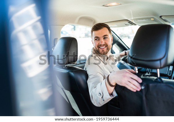 Smiling man driving in\
reverse on car