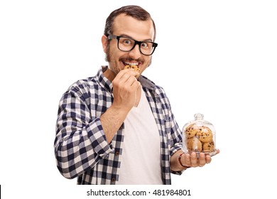 Smiling man eating a cookie and holding a jar full of cookies isolated on white background