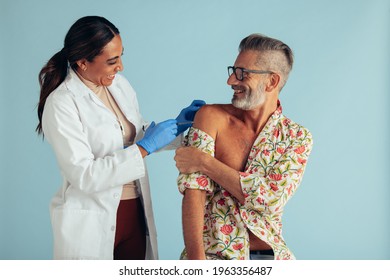 Smiling Man Getting Flu Shot From A Female Doctor. Female Healthcare Professional Giving Vaccine To Mid Adult Man.