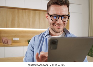 Smiling man in glasses, engaging with a tablet in a light and modern office space.

 - Powered by Shutterstock