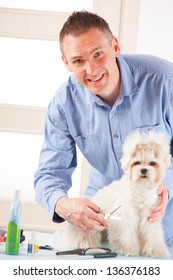 Smiling Man Grooming A Dog Purebreed Maltese.