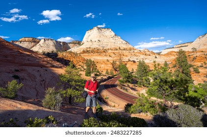 Smiling man hiking in red mountains in Utah. Man hiker relaxing in the mountains on summer vacation. Man enjoying time in nature. Zion National Park, Springdale, Utah, USA. - Powered by Shutterstock