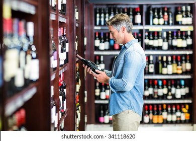 Smiling man holding bottle of wine in supermarket