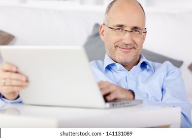 Smiling Man Holding Laptop While Leaning On The Couch At Home