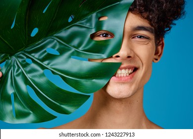 Smiling Man Holding A Large Leaf Of A Plant Near The Face                     