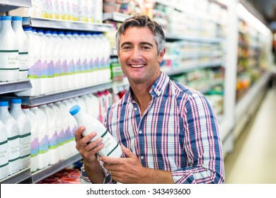 Smiling Man Holding Milk Bottle In The Supermarket