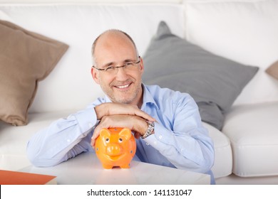 Smiling man holding piggybank at the living room