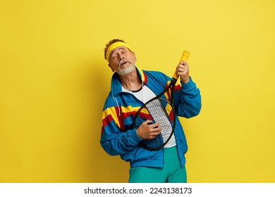 Smiling Man Holding Tennis Rocket. Funny Senior Tennis Player Playing At Rocket Isolated On Yellow Studio Background. Excitement In Game, Human Emotions, Facial Expression And Passion With Sport 