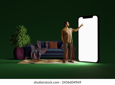 Smiling man in home wear standing in room and pointing at big mobile phone screen, using online services for shopping. 3D model of phone. Mockup for ad, text, design, logo. Ad, sales